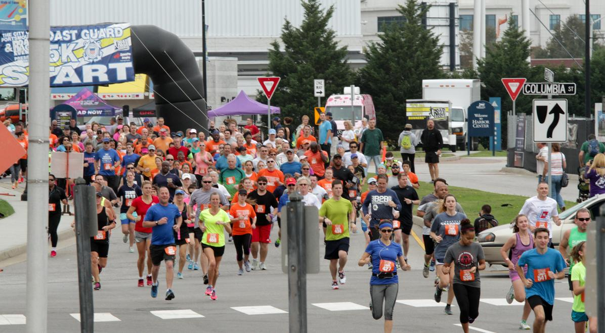 A large crowd of runners crossing the start line at the Coast Guard Race in downtown Portsmouth, Virginia